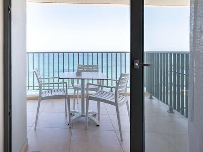 Balcon avec table et chaises donnant sur la mer par une journée ensoleillée.