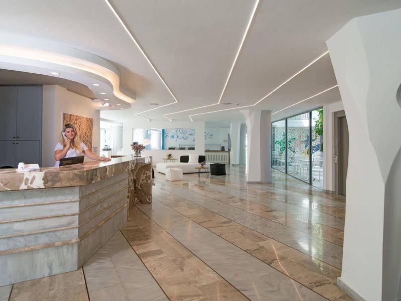 Hall d'hôtel lumineux avec comptoir d'accueil, sol en marbre brillant et design intérieur moderne.