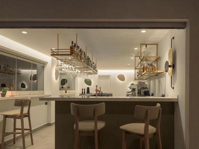 Bar moderno de hotel con taburetes de madera, estantes para vino y luz tenue.