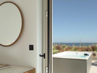 Interior moderno con gran espejo y vista a la terraza con jacuzzi y mar.