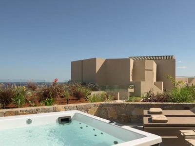 Jacuzzi y tumbonas en terraza con vista a edificios modernos y cielo azul