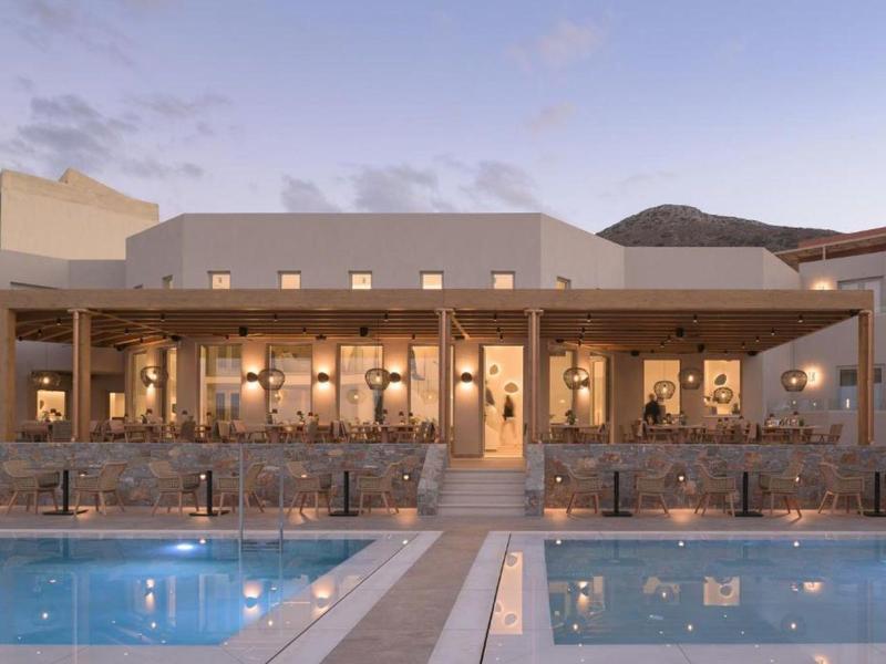 Edificio de hotel moderno con piscina en primer plano al anochecer