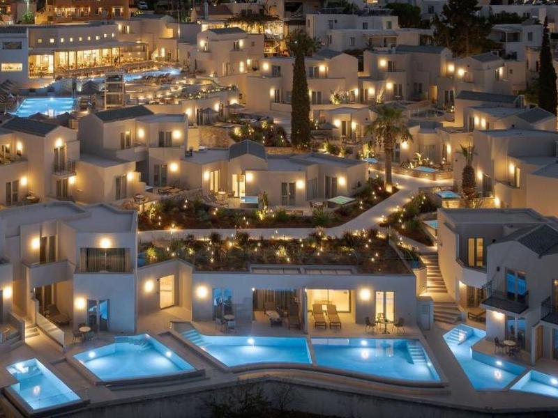 Vista de un hotel iluminado con varias piscinas por la noche