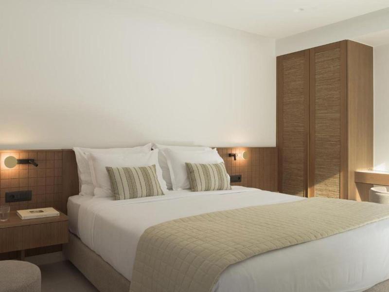 Dormitorio luminoso con cama grande, mesitas de noche y armario de madera