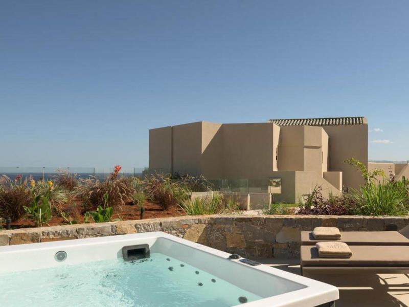 Jacuzzi y tumbonas en terraza con vista a edificios modernos y cielo azul