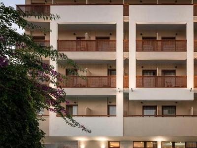 Moderner mehrstöckiger Gebäudekomplex mit Balkonen und beleuchtetem Pool am Abend.