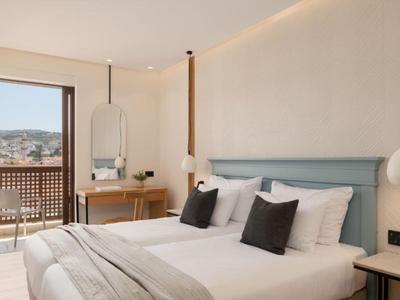 Habitación de hotel moderna con cama doble, escritorio y balcón con vista a la ciudad.