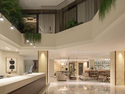 Área de lobby de hotel luminosa y moderna con asientos y plantas verdes colgantes.