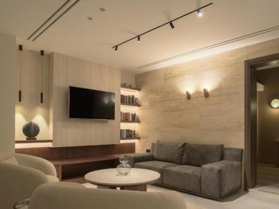 Sala moderna con sofá gris, sillones, televisor e iluminación indirecta.