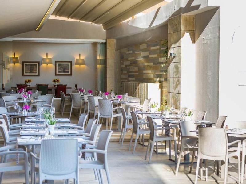 Bright, modern dining area with white chairs and tables decorated with flowers.