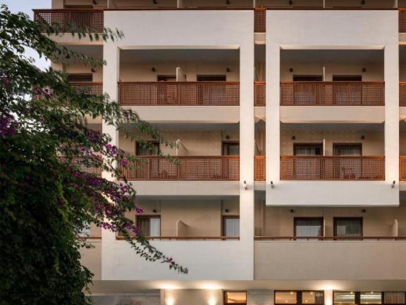 Modern hotel building with illuminated pool and balconies at dusk