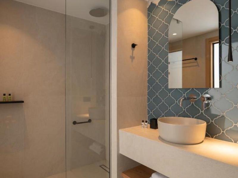 Modern bathroom with glass shower, round mirror, and sink on a light countertop.