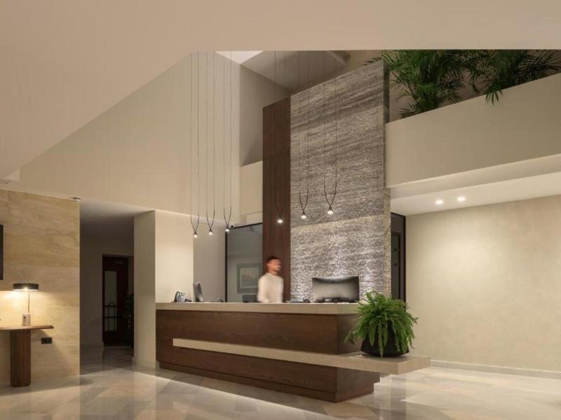 Modern hotel lobby with reception desk and friendly staff, subtle lighting and plants.
