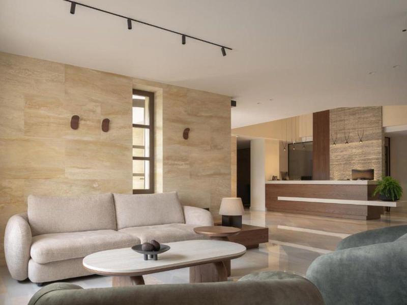 Modern hotel lounge area with sofa, coffee tables, and reception desk.