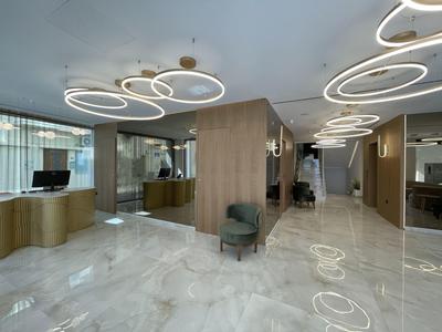 Moderne Lobby mit hellen Marmorböden, runden LED-Leuchten und holzverkleideten Wänden.