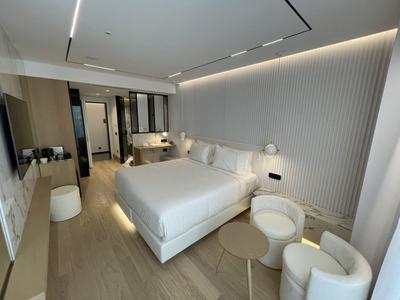 Moderní hotelový pokoj s velkou manželskou postelí, posezením a minimalistickým designem.