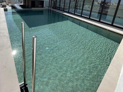 Moderní čistý bazén na terase se skleněným zábradlím v slunečný den.