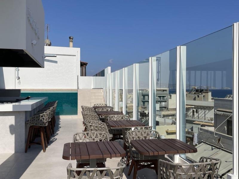 Terrazza panoramica con tavoli e sedie moderni accanto a ringhiera in vetro e area bar.