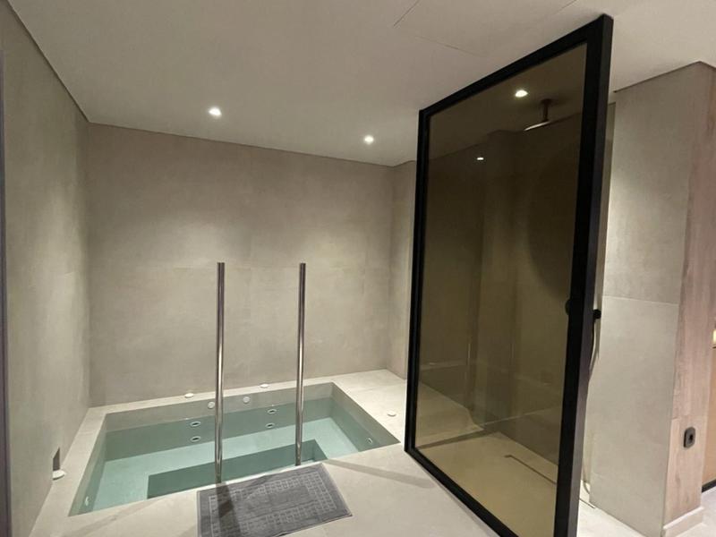 Area benessere moderna con piccola piscina, scaletta in acciaio e porta scorrevole in vetro.