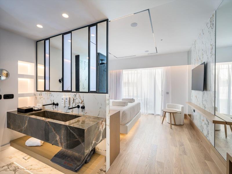 Camera d'hotel moderna con lavabo in marmo, pavimento in legno e luce naturale da grandi finestre