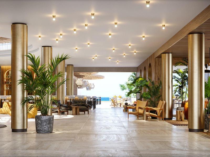 Großer heller Eingangsbereich mit goldenen Säulen, Pflanzen und moderner Beleuchtung, Blick aufs Meer.