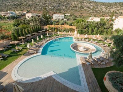 Großer Hotelpool mit Sonnenschirmen und Liegestühlen in hügeliger Landschaft.