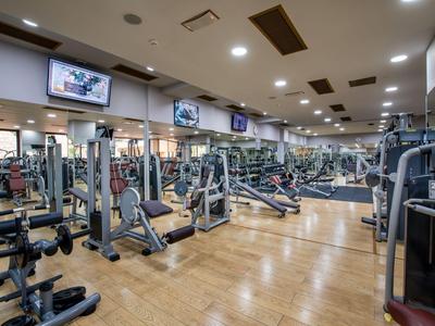 Moderner Fitnessraum im Hotel mit vielfältigen Trainingsgeräten und Holzfußboden.