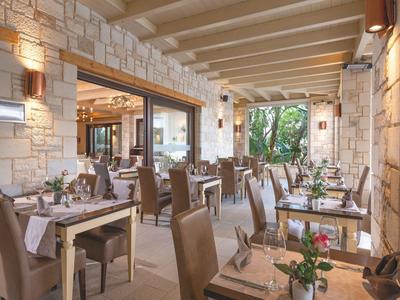 Ein stilvolles Restaurant mit Holzbalkendecke und Steinwänden, dekoriert mit frischen Blumen auf Tischen.