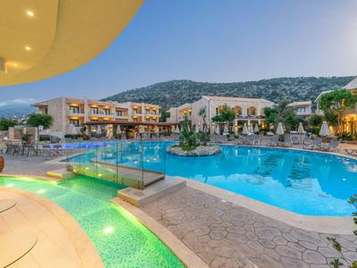 Moderner Hotelpoolbereich mit beleuchtetem Wasserfall und Panoramablick auf Berge.