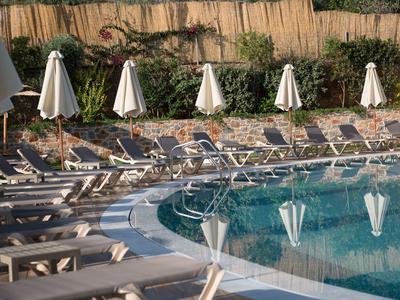 Poolbereich mit Liegestühlen und geschlossenen Sonnenschirmen an einem Hotel.