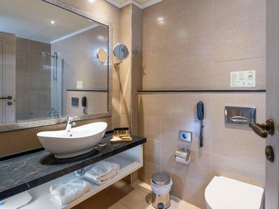 Modernes Hotelbadezimmer mit großem Spiegel, Waschbecken auf schwarzer Arbeitsplatte und Toilette.