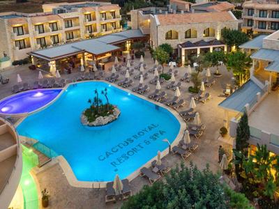 Hotel mit beleuchtetem Poolbereich, umliegenden Liegestühlen und mediterraner Architektur.