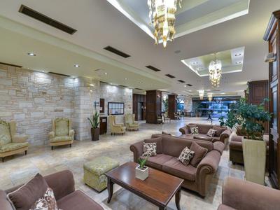 Heller Hotel-Loungebereich mit Sitzgruppen, Steinen dekorierten Wänden und moderner Beleuchtung.