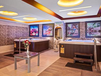 Large wellness area with two hot tubs, flowers, and modern lighting.