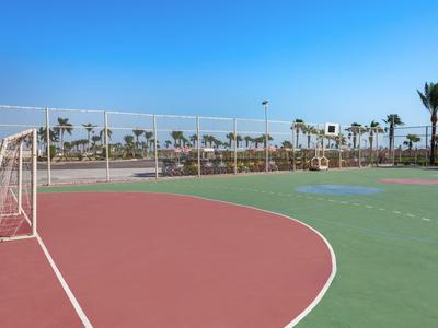 Otwarte boisko sportowe z bramką do piłki nożnej i czystym niebem, otoczone palmami.