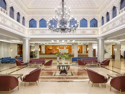 Duży, elegancki hol hotelowy z fotelami i żyrandolem.