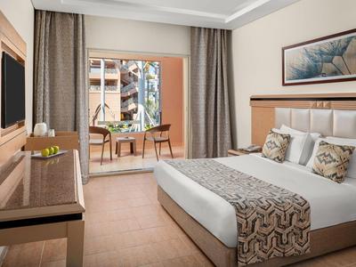 Nowoczesny pokój hotelowy z łóżkiem podwójnym, biurkiem, krzesłami i balkonem z widokiem.