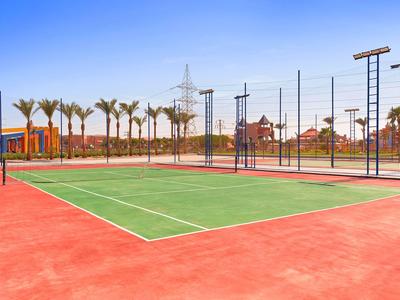 Ein Außen-Tennisplatz mit rotem Belag und grüner Spielfläche vor blauem Himmel.
