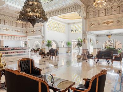 Gran vestíbulo de hotel con sillas elegantes, mesas y lámparas bajo un techo decorado y luminoso