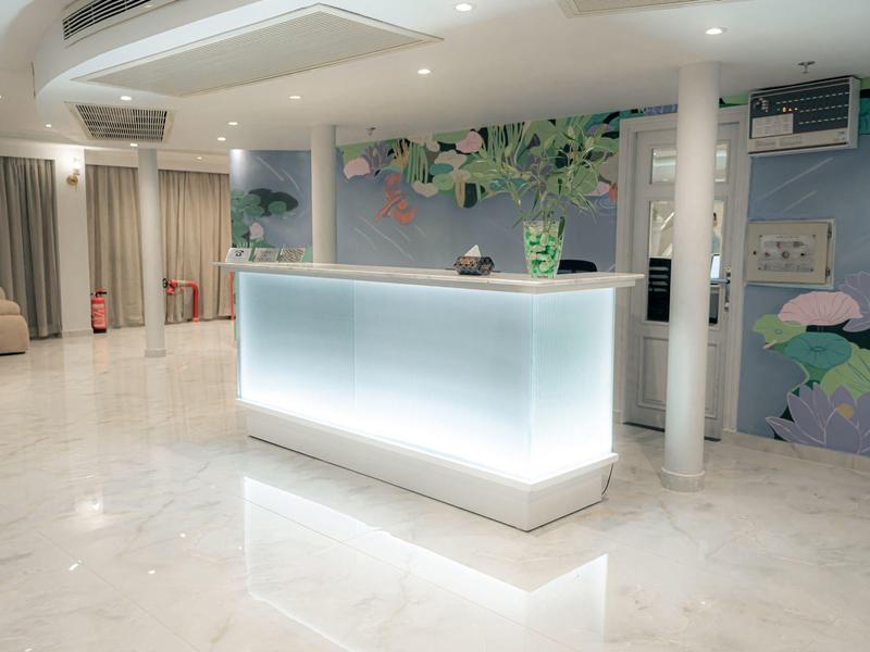 Moderne hotelreceptie met verlicht bureau en bloemmuurschildering in heldere, schone hal.