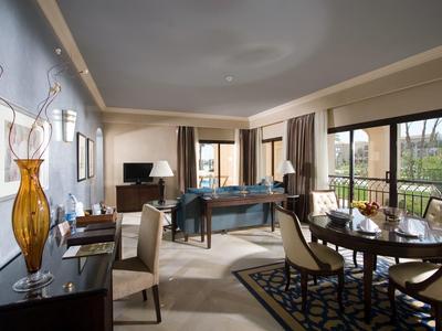 Ruime hotelsuite met biljarttafel, eetgedeelte en balkon met uitzicht op groen.