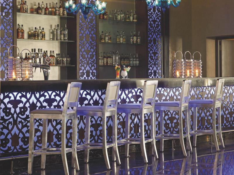 Elegante hotelbar met ingewikkeld blauw patroon op de muur, gloeiende kroonluchter en zes hoge stoelen