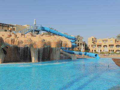 Großer Pool mit blauem Wasserrutschen und felsiger Gestaltung unter klarem Himmel