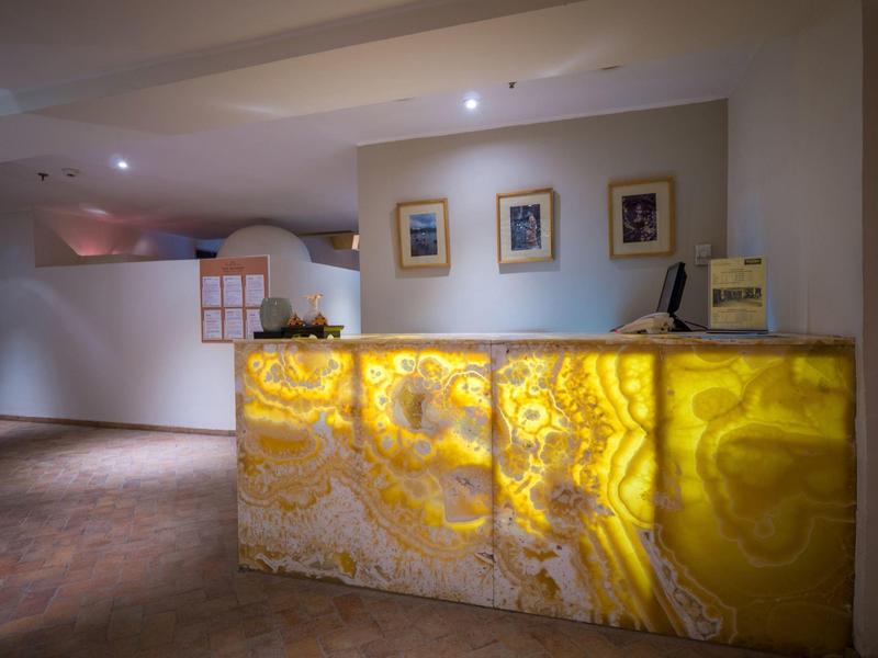 Hotelrezeption mit beleuchtetem Onyx-Empfangstresen und drei Bildern an der Wand.