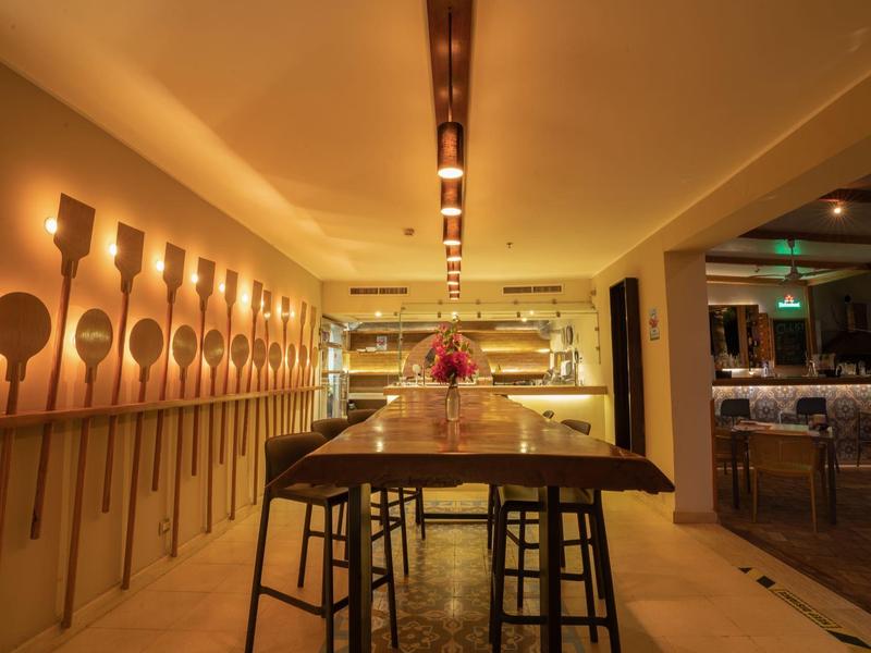 Modernes Restaurant mit Holztischen, Hockern und dekorativen Holzlöffeln an der Wand.