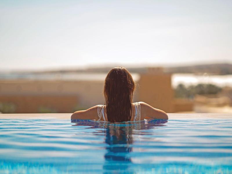 Frau entspannt sich im Pool mit Blick auf eine weite Landschaft.