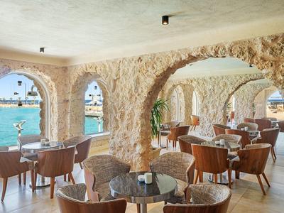 Gezellige zitplaatsen met stenen zuilen en uitzicht op zee in een hotelrestaurant.