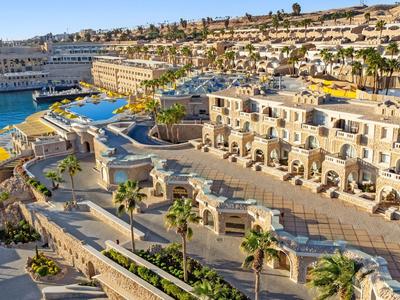 Luxe resort met zwembaden aan de kust, omgeven door palmbomen en zeezicht.