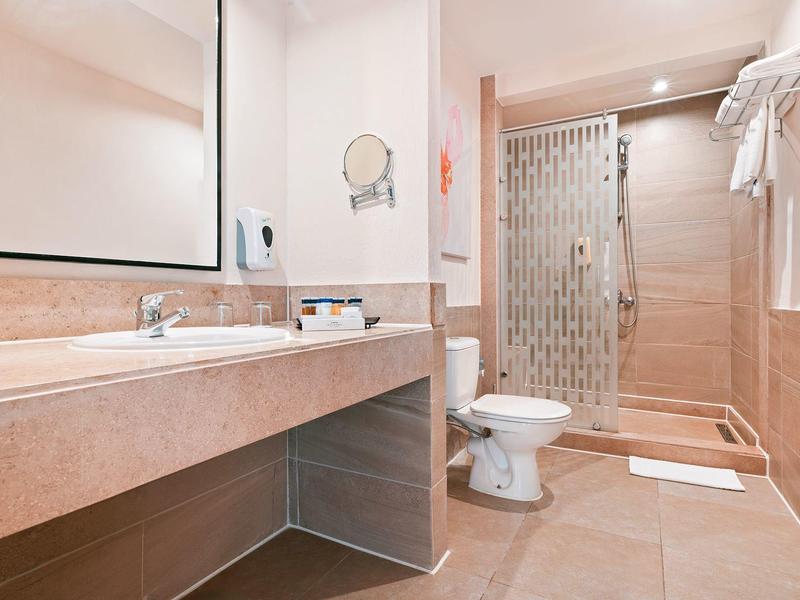 Moderne badkamer met grote spiegel, wastafelblad, toilet en inloopdouche met glazen deur.