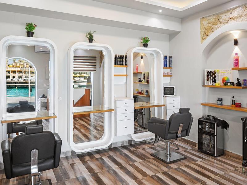 Moderne kapsalon met grote spiegels, twee stoelen en houten vloer.